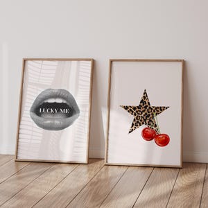 May include: Two framed prints, one with a black and white illustration of a pair of lips with the text "LUCKY ME" and the other with a black star with a leopard print pattern and two red cherries.
