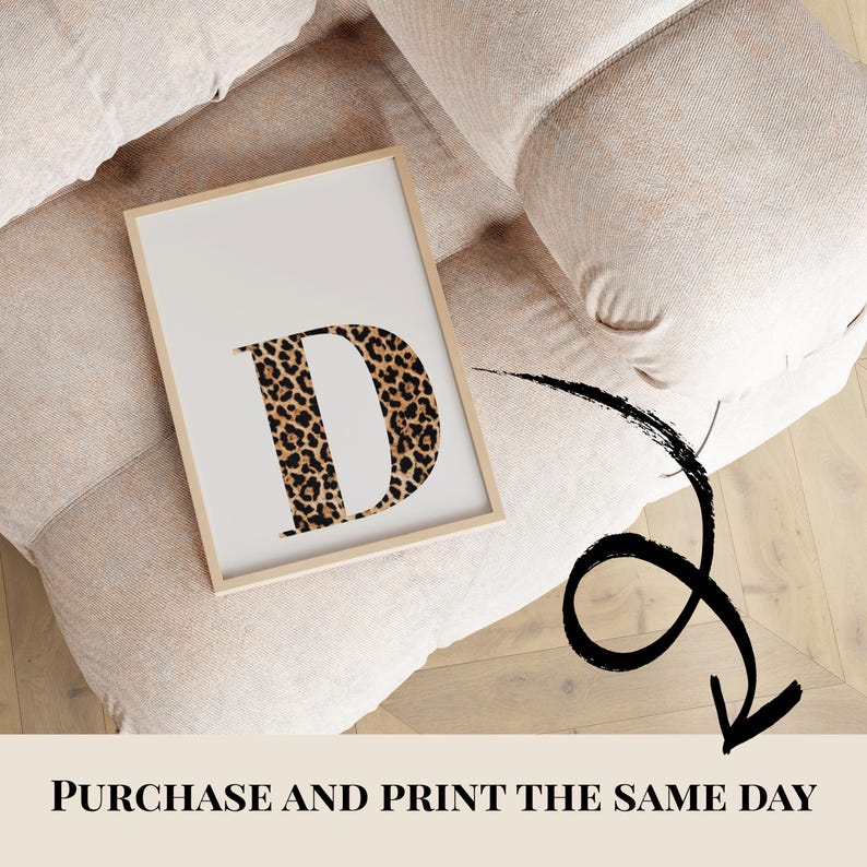 May include: A framed print featuring the letter "D" in a leopard print design. The print has a white background and a light wooden frame. The text "PURCHASE AND PRINT THE SAME DAY" is at the bottom of the image.