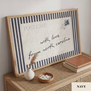 May include: A framed rectangular print featuring a vintage postcard design with navy blue and white vertical stripes. The text reads POST CARD and with love from north carolina, accompanied by a small stamp illustration and a circular postmark.
