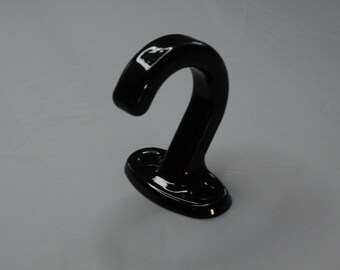 May include: Black metal hook with a curved design. The hook is mounted on a flat base.