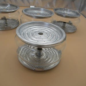 Peut inclure: Quatre paniers filtrants en verre transparent pour cafetière avec des couvercles en métal et un bec central.