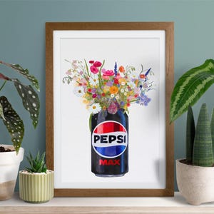 May include: A framed art print featuring a Pepsi Max can filled with a vibrant bouquet of colorful flowers. The can is black with the Pepsi logo in red, white, and blue. The artwork is displayed on a white surface with potted plants on either side.