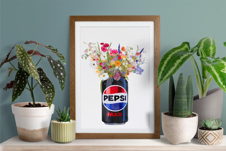 May include: A framed art print featuring a Pepsi Max can filled with a vibrant bouquet of colorful flowers. The can is black with the Pepsi logo in red, white, and blue. The artwork is displayed on a white surface with potted plants on either side.