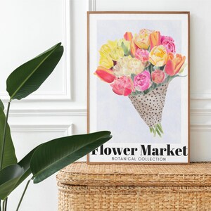 May include: A framed art print featuring a watercolor bouquet of tulips in shades of yellow, pink, and orange, presented in a dotted cone. The print is labeled "Flower Market, Botanical Collection."