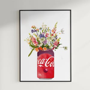 May include: Framed art print showing a colourful floral display in a red Coca-Cola can. The can has the Coca-Cola logo in white script. The flowers are a mix of pink, purple, yellow, and white. The artwork is set against a white background.