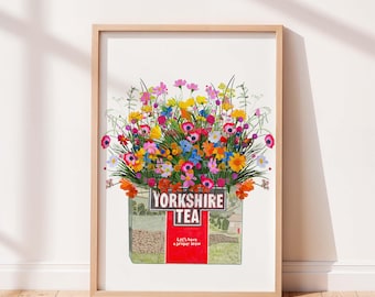 May include: A framed art print featuring a vibrant bouquet of colorful wildflowers emerging from a Yorkshire Tea box. The box displays the text Yorkshire Tea and Let's have a proper brew, set against a background of green fields and stone walls.