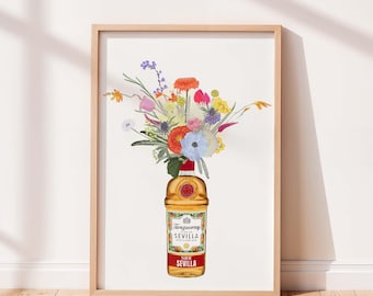 Pode incluir: Uma impressão artística emoldurada apresentando uma garrafa de gin Tanqueray Flor de Sevilla usada como vaso, cheia com um buquê colorido de flores laranja, amarelas, rosas, azuis e brancas, sobre fundo branco em uma moldura de madeira clara.