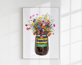 May include: A framed art print featuring a Branston Original pickle jar used as a vase, filled with a vibrant bouquet of colourful wildflowers including pink, yellow, blue, and orange blossoms against a plain white background.