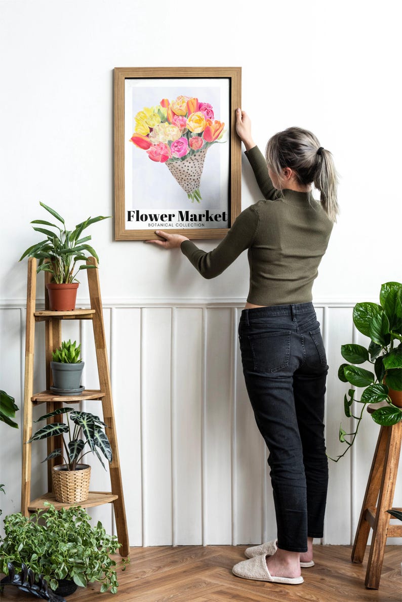 May include: A framed print featuring a watercolor illustration of a bouquet of flowers in shades of yellow, pink, and orange. The print is labeled "Flower Market Botanical Collection". The frame is a light brown color.