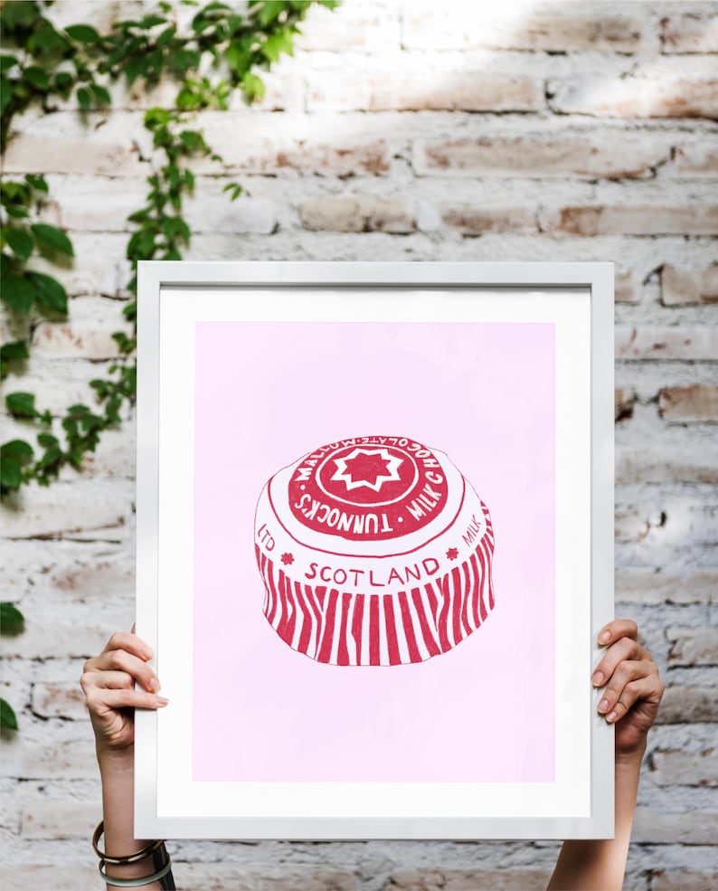 May include: A framed print featuring a red and white illustration of a Tunnock's Milk Chocolate wafer. The print includes the text "Tunnock's Milk Chocolate" and "Scotland" on a pink background.