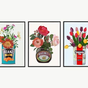 May include: Three framed art prints featuring floral arrangements in food containers. One shows flowers in a Beanz can, another in a Marmite jar, and the last in a Yorkshire Tea box. Each print has a white background.