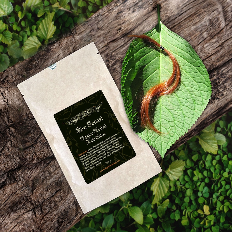 May include: A brown paper packet with a label that reads "Fire Genasi Copper Herbal Hair Color" and lists ingredients. The packet is on a wooden surface with a green leaf and a strand of copper-colored hair.