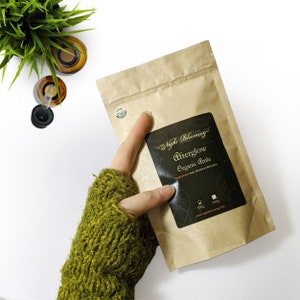 Puede incluir: Una bolsa de papel marrón con una etiqueta negra que dice "Night Blooming Afterglow Organic Amla". La etiqueta también incluye los ingredientes "Amla (Emblica Officinalis)" y el texto "100g 500g www.nightblooming.com".