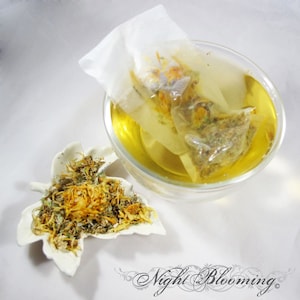 May include: A clear glass bowl filled with yellow liquid, with a tea bag steeping inside. A white leaf-shaped dish holds dried herbs and flower petals. The image is set against a white background. The text "Night Blooming" is at the bottom.