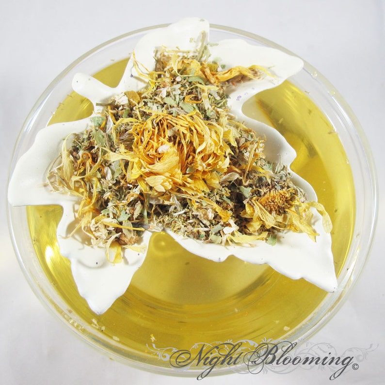 May include: A clear glass bowl filled with a golden liquid, with a white leaf-shaped ceramic dish holding a mix of dried herbs and flowers. The text "Night Blooming" is visible in the bottom right corner.