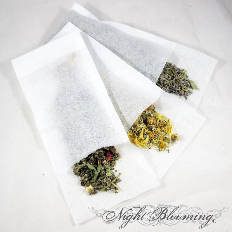 May include: Four white muslin tea bags filled with different dried herbs. The herbs include lavender, chamomile, and a blend of green herbs. The bags are arranged in a fan shape on a white background. The text "Night Blooming" is visible at the bottom of the image.