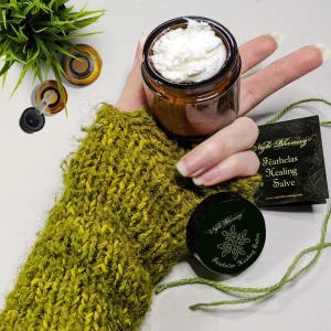 May include: A brown glass jar filled with a white salve. The jar has a black label with the text "Night Blooming" and "Feathclas Healing Salve".