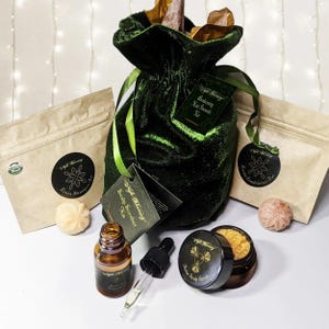 May include: A green velvet bag with a label that reads "Boosting Hair Growth Kit". The bag is surrounded by various hair care products, including a shampoo bar, a conditioner bar, a scalp smoother kit, a scalp scrub, and a bottle of oil.