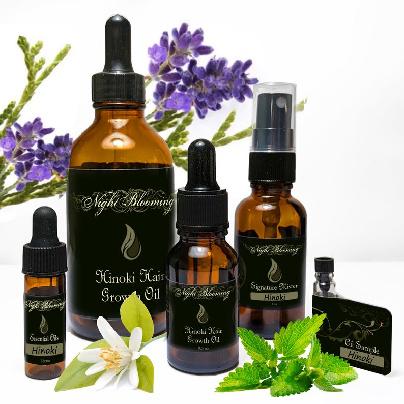 Puede incluir: Un conjunto de cuatro botellas de vidrio &aacute;mbar con goteros y pulverizadores. Las botellas est&aacute;n etiquetadas con "Night Blooming" y contienen aceite de crecimiento capilar Hinoki y aceites esenciales Hinoki. Las botellas est&aacute;n dispuestas sobre una superficie blanca con hojas verdes y flores moradas.