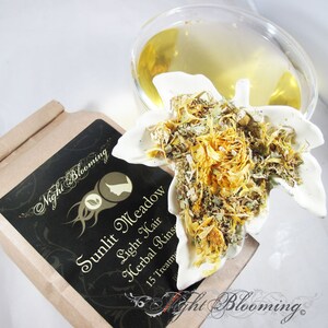 May include: A brown paper box with a black label that reads "Sunlit Meadow Light Hair Herbal Rinse 15 Treatments" and a white ceramic leaf-shaped dish filled with dried herbs and flowers.