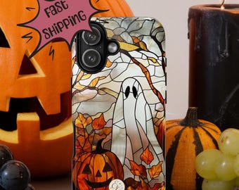 May include: A smartphone case with a stained-glass design featuring a white ghost, pumpkins, and autumn leaves. The case has a black camera module and the words "Fast Shipping" on a pink banner. The background includes a carved pumpkin, candles, and grapes.