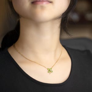 Op de afbeelding: Een gouden ketting met een vierbladige klaver hanger gemaakt van groene edelstenen.