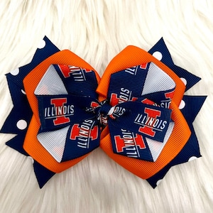May include: A blue and orange hair bow with white polka dots and the text "ILLINOIS" repeated on the bow.