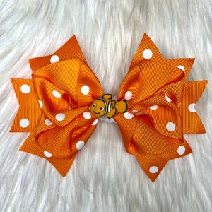 Peut inclure: Noeud pour cheveux orange à pois blancs avec un petit charme de poisson orange et blanc au centre.