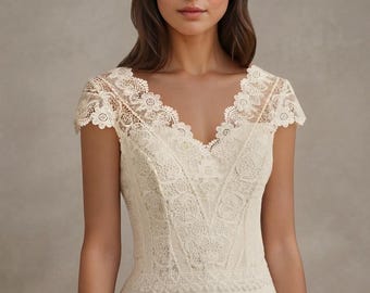 May include: An ivory-colored top featuring a V-neckline and cap sleeves, constructed with intricate floral lace detailing across the bodice and shoulders, transitioning into a smooth, solid-colored fabric at the waistline.