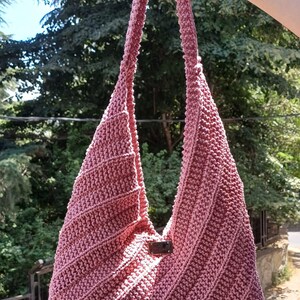 Pu&ograve; includere: Una borsa hobo all'uncinetto color rosa polvere con una trama a coste diagonali e un unico manico integrato. Una piccola etichetta rettangolare in similpelle marrone &egrave; posizionata al centro della parte anteriore della borsa.