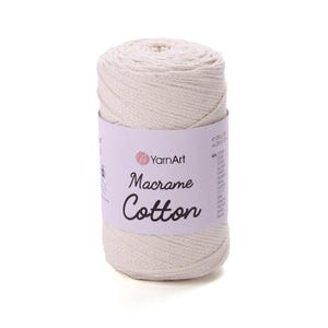 May include: A cylindrical spool of off-white macrame cotton cord wrapped in a light purple paper label. The label features the YarnArt logo and the text Macrame Cotton in a black script font, with 250g and 225m printed on the side.
