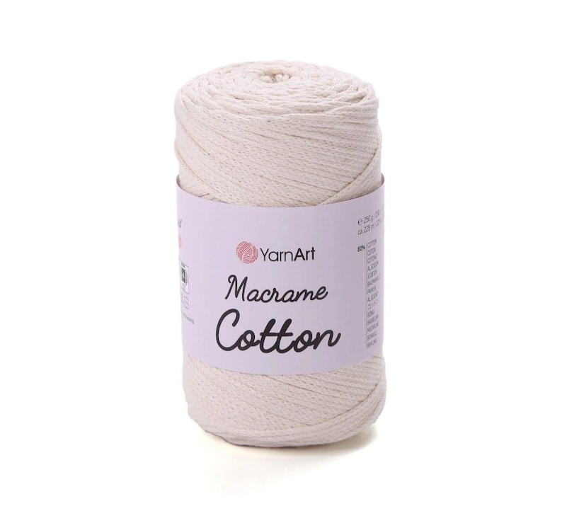 May include: A cylindrical spool of off-white macrame cotton cord wrapped in a light purple paper label. The label features the YarnArt logo and the text Macrame Cotton in a black script font, with 250g and 225m printed on the side.