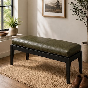 May include: A rectangular bench featuring a dark olive green faux leather upholstered seat with a central seam. The bench is supported by a sturdy black wooden frame with four straight, slightly tapered legs that provide a stable base.