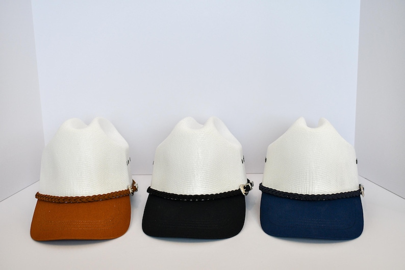 May include: Three white cowboy hats with different colored brims. The hats have a brown, black, and blue brim.