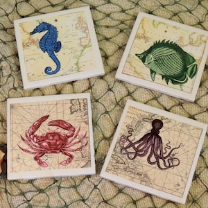 May include: Set of four ceramic coasters featuring vintage nautical illustrations. The coasters depict a blue seahorse, a green fish, a red crab, and a purple octopus. Each coaster has a beige background with a vintage map design.