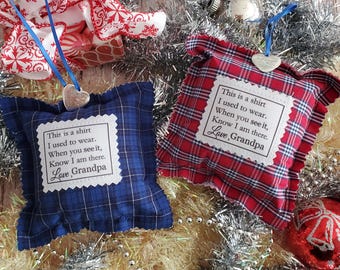 May include: Two square fabric ornaments, one in blue plaid and one in red plaid, each featuring a white patch with the printed text: This is a shirt I used to wear. When you see it, Know I am there. Love, Grandpa. Both hang from blue ribbons.