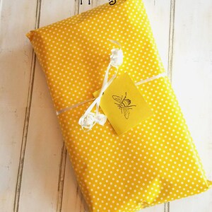 May include: A yellow gift box with white polka dots, wrapped with a white ribbon and a yellow tag with a bee illustration. The tag reads "Gift Wrapping Available!"