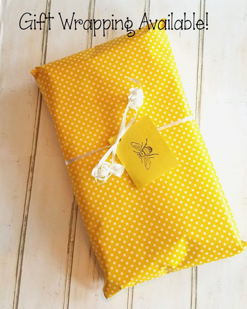 May include: A yellow gift box with white polka dots, wrapped with a white ribbon and a yellow tag with a bee illustration. The tag reads "Gift Wrapping Available!"