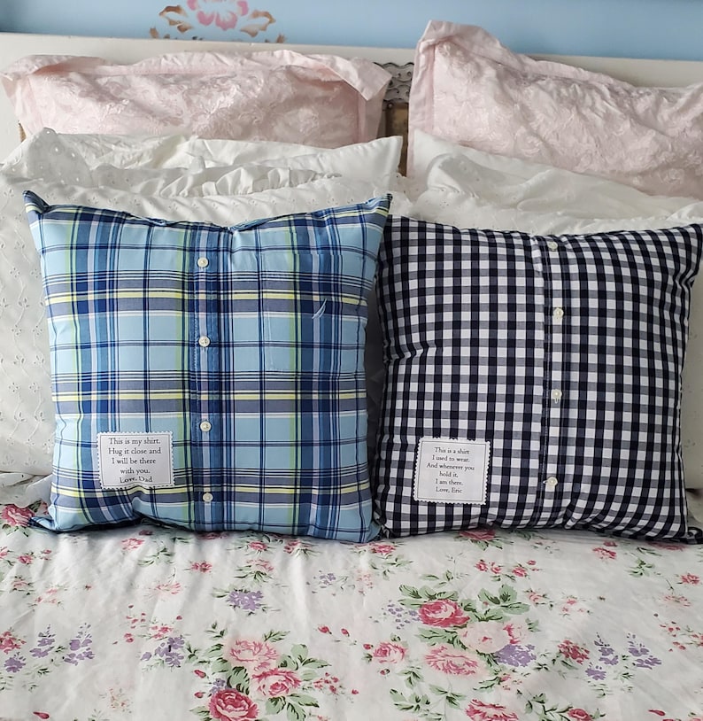 Two square throw pillows made from repurposed shirts. One is blue plaid, the other black and white gingham. Each pillow has a button-down front and a small white tag with text.