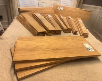 May include: A collection of light brown rectangular wooden boards arranged in multiple stacks. The boards feature a natural wood grain pattern and smooth surfaces. Several individual boards have white rectangular price tags attached to them.