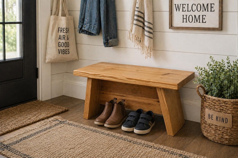 May include: A wooden bench with a natural finish sits in a hallway. Two pairs of shoes are placed underneath the bench. A tote bag with the text "FRESH AIR & GOOD VIBES" hangs on the wall. A sign that says "WELCOME HOME" is also on the wall.