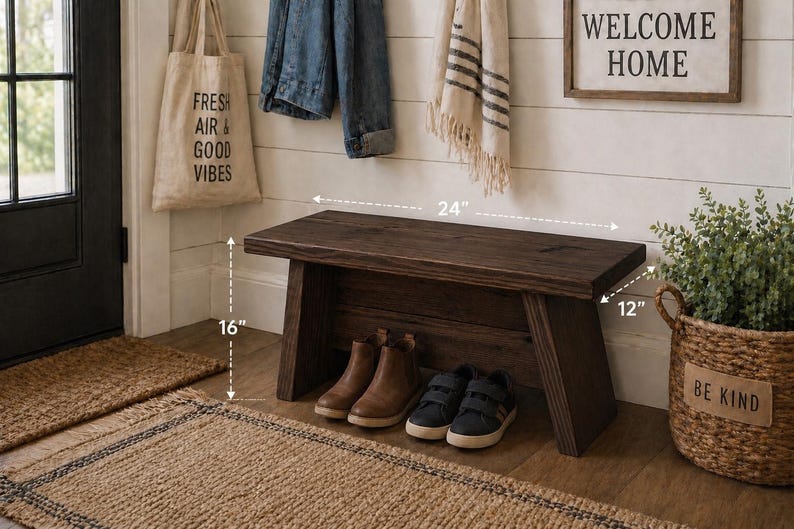 May include: A dark brown wooden bench, 24 inches long, 16 inches high, and 12 inches deep, with shoes underneath. A tote bag with "FRESH AIR & GOOD VIBES" hangs nearby. A sign says "WELCOME HOME". A basket with a plant and a "BE KIND" tag is also present.