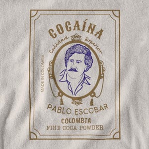 May include: A gold-framed label with the text "Cocaína Calidad Superior" and a portrait of Pablo Escobar. The label also reads "Made in Colombia, Pablo Escobar, Colombia, Fine Coca Powder."