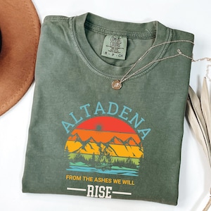 May include: Green t-shirt with a sunset graphic and the text "Altadena From the Ashes We Will Rise".