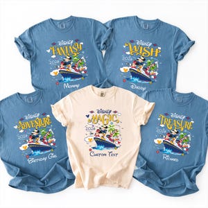 May include: A collection of light blue and cream-colored t-shirts featuring Disney cruise ship designs. Each shirt has a different theme: Fantasy, Wish, Adventure, Magic, and Treasure. The shirts include the year 2026 and character illustrations.