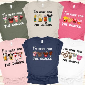 May include: Collection of t-shirts in various colors, each featuring the phrase "I'M HERE FOR" above a graphic of snacks or drinks. Designs include ice cream, popcorn, pretzels, and beverages.