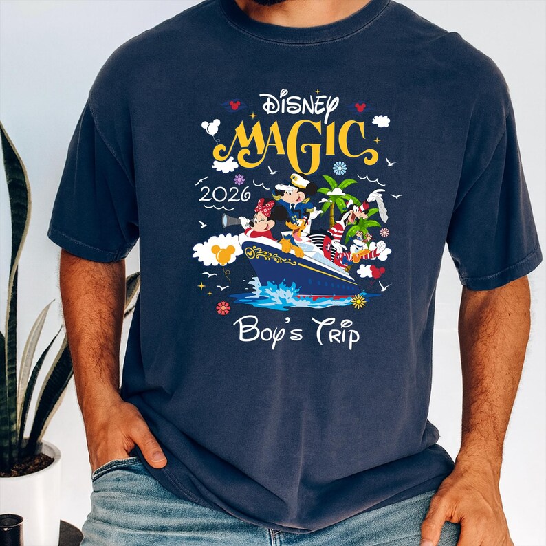 May include: Navy blue t-shirt featuring the words "Disney Magic 2026 Boy's Trip" with a graphic of Mickey and Minnie Mouse on a cruise ship. The design includes palm trees, birds, and decorative elements.