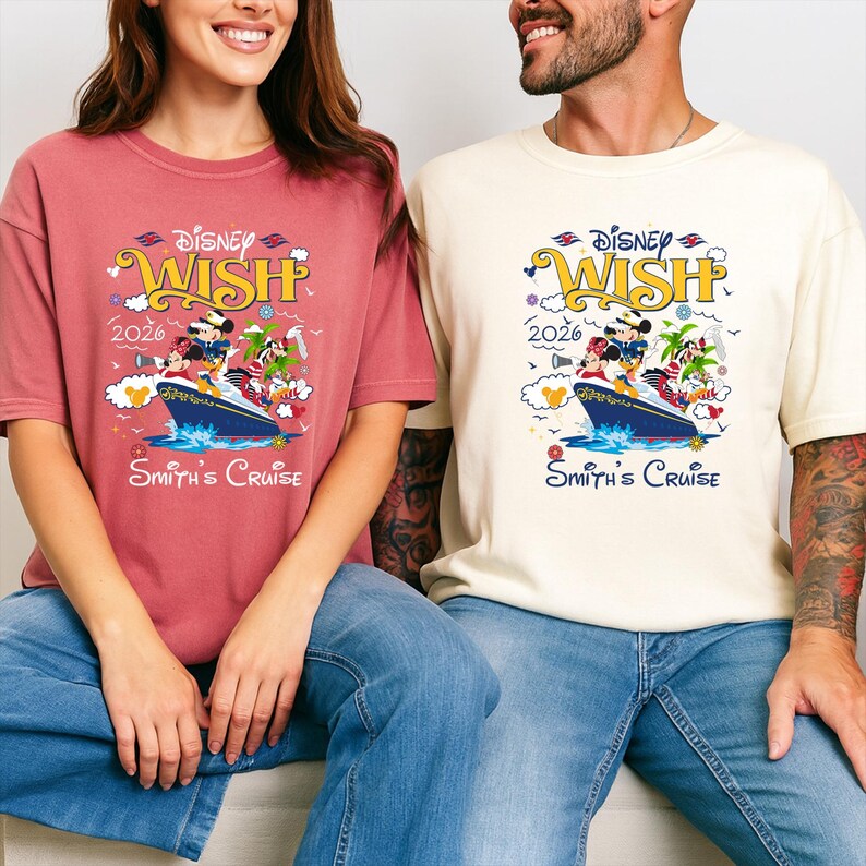 May include: Two t-shirts, one in a dusty rose color and the other in cream, each featuring a colorful graphic. The graphic includes the text "Disney Wish 2026" and a cruise ship with Disney characters. The text "Smith's Cruise" is below the ship.