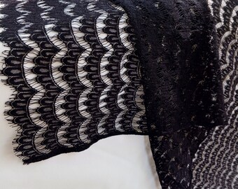 May include: Black lace fabric with a scalloped edge. The lace has a delicate pattern of small circles and curves.