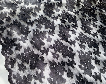 Peut inclure: Tissu de dentelle noire avec un motif floral. La dentelle est délicate et a une texture douce et fluide.